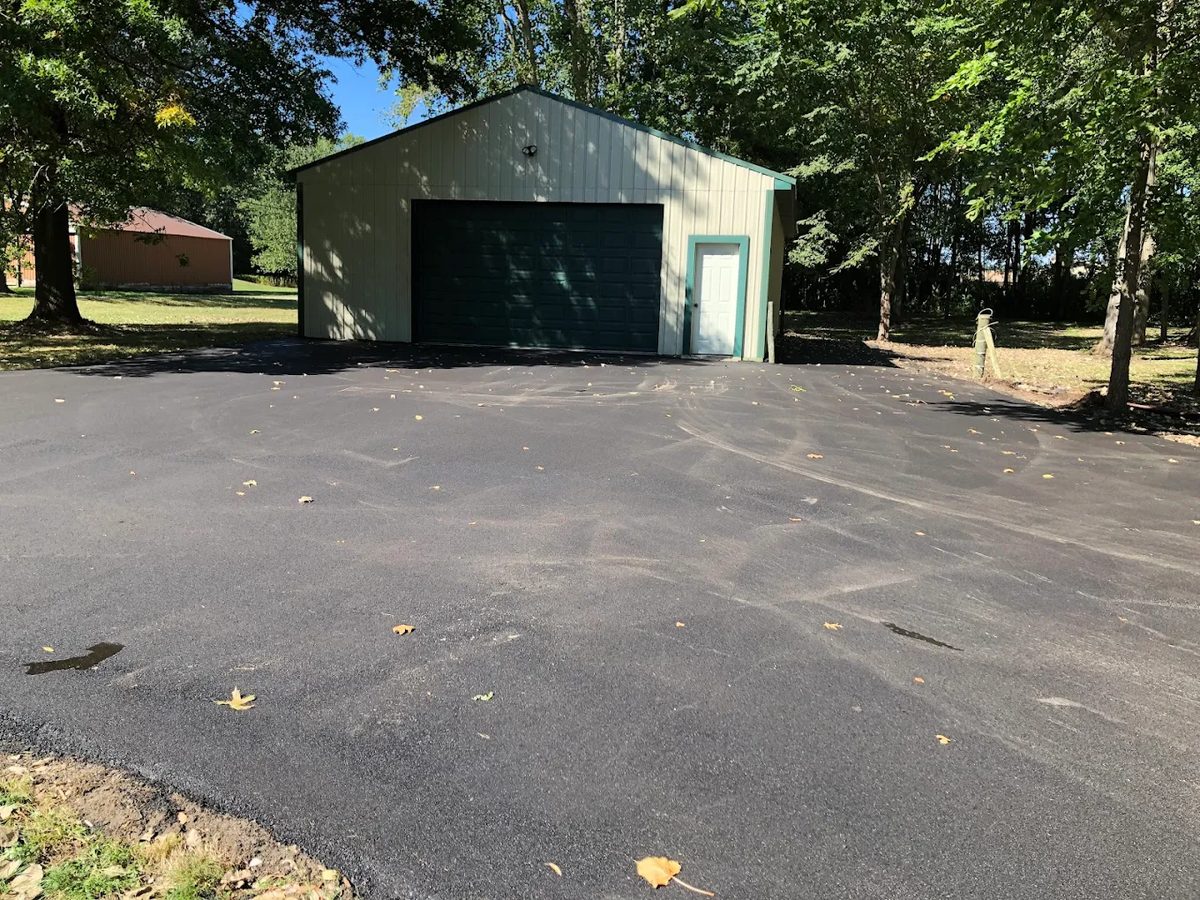 New asphalt driveway up to an attached garage